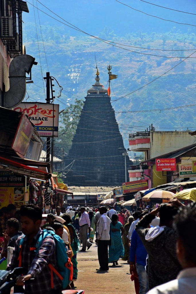 पार्किंग से त्र्यंबकेश्वर मंदिर का गुम्बद और उसके पीछे त्र्यंबक पर्वत दिखाई देते हैं।  